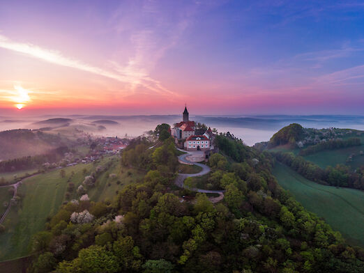 Burg auf einem Berg bei Sonnenuntergang.