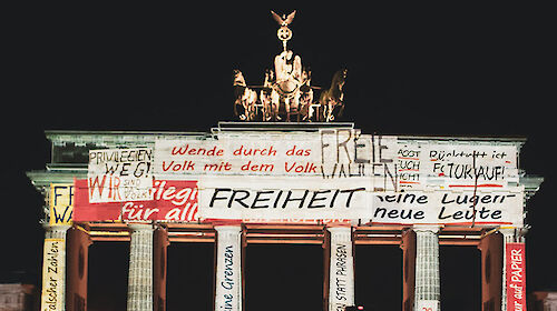 Brandenburger Tor mit Projektion von verschiedenen Schriftzügen zum Thema Freiheit und Wiedervereinigung.